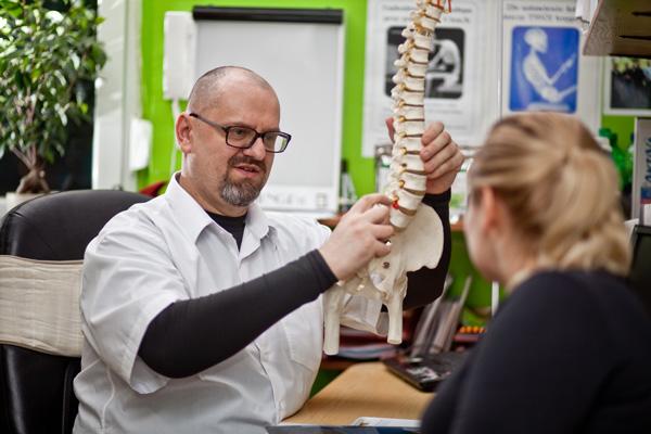 Chiropraktyk z modelem kręgosłupa podczas konsultacji przed terapią metodą McTimoney-Corleya, Poznań