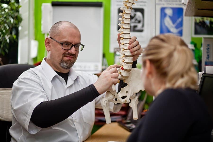 Przemysław Rybczyński, chiropraktyk z Poznania, omawia z pacjentką model kręgosłupa podczas konsultacji